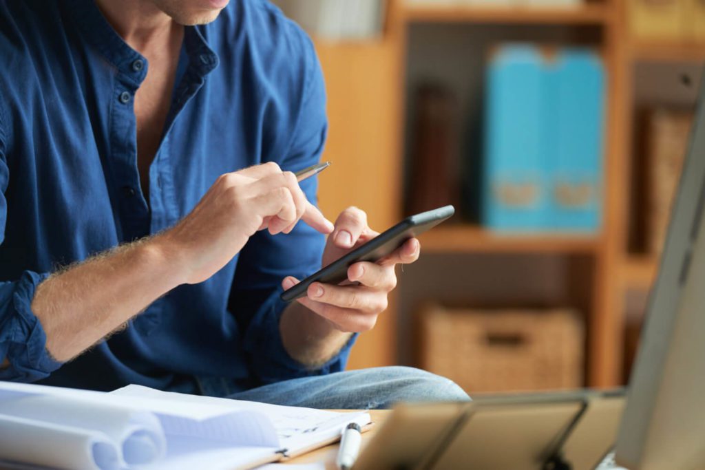 casually-dressed-unrecognizable-man-using-smartphone-work-office